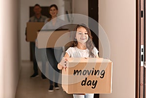 Little girl and her parents with cardboard boxes indoors. Moving into new apartment