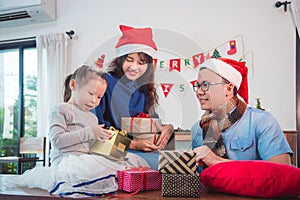 Little girl and her parents open christmas gift boxes