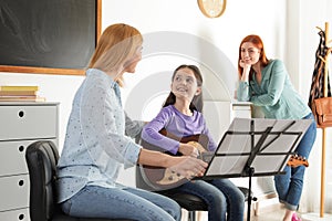 Little girl with her teacher and mother at music lesson