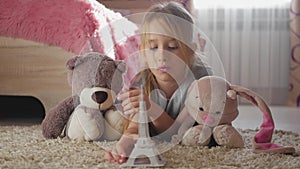 Little girl with her toys at children room dreaming about travel to Paris. Child dream, vacation and travel concept.