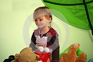 Little girl sits in the middle of all her stuffed animals