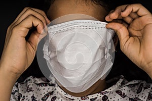 Little girl hide away from the virus covering all her face with a white surgical mask. Concept of fear of contagion