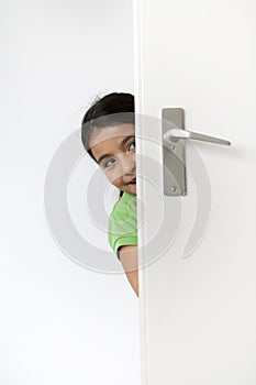 Little girl is hiding behind the door