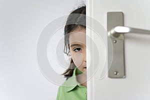 Little girl is hiding behind the door