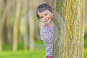 Little girl hiding behind a tree