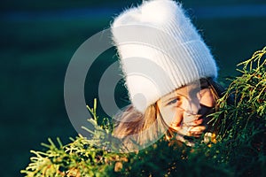 Little girl hiding behind a tree. Happy child having fun in the park