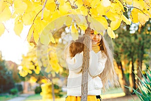 Little girl hiding behind a tree. Happy child on the walk in autumn park