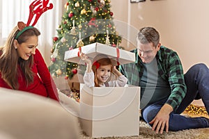 Little girl hiding inside giant Christmas present while playing hide and seek