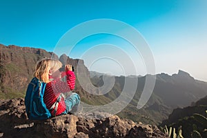 Little girl hiking in mountains looking at binoculars, famly travel