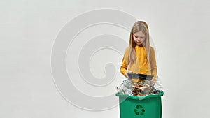 Little girl hold plastic plate from full dustbin