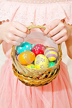 Little girl holding a basket whith handmade painted easter eggs