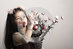 Little girl holding a bouquet of artificial flowers in glass vase