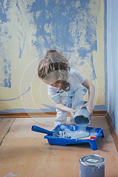 Little girl holding canister with paint at her room, making renovation.