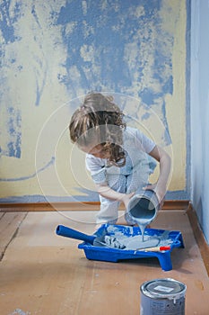 Little girl holding canister with paint at her room, making renovation.