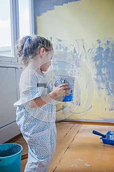 Little girl holding canister with paint at her room, making renovation.