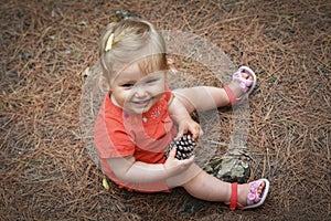 Little girl holding a cone in the woods forest