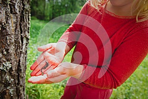 Little girl holding and exploring lizard in forest, eco-friendly lifestyle