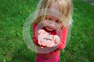 Little girl holding and exploring lizard in nature