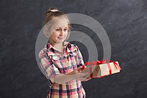 Little girl holding gift box on dark background