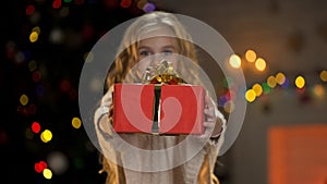 Little girl holding gift box, sharing presents with orphaned children at Xmas photo