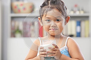 Little girl holding glass of milk