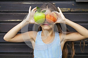 Little girl holding a green apple and a peach