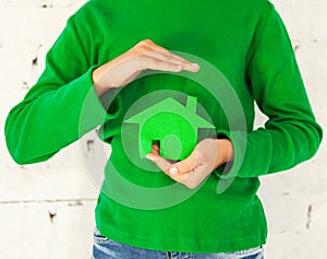 Little girl holding green house in hands