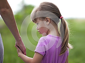 Little girl holding a hand of her mother. Family relations concept.