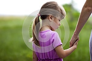 Little girl holding a hand of her mother. Family relations concept.