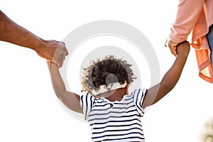 Little girl holding hands with her parents.