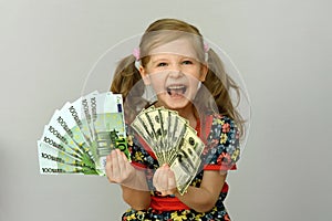 Little girl holding in hands a pack of dollars and Euro