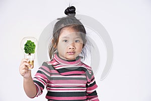 Little girl holding light bulb with a tree