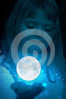 Little girl holding the moon and stars on the palm of her hand