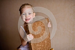 A little girl is holding a photo book in natural brown leather