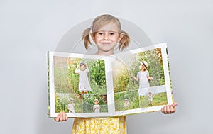 A Little girl holding a photobook with her photographs in her handspt