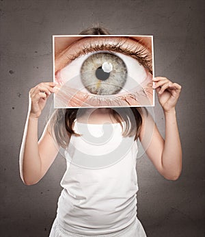 Little girl holding a picture of an eye watching