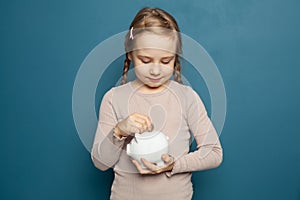 Little girl holding a piggy bank and inserting a one euro coin
