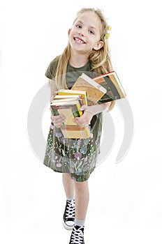 Little girl holding pile of school books grinning happily. Back to school concept.