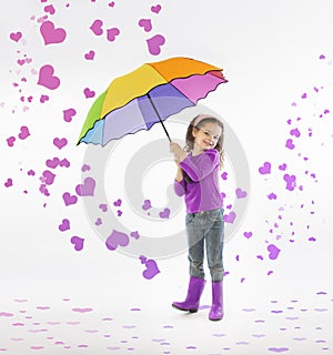 Little girl holding rainbow umbrella in storm of pink hearts