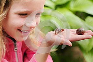 Little girl holding snails on her hand