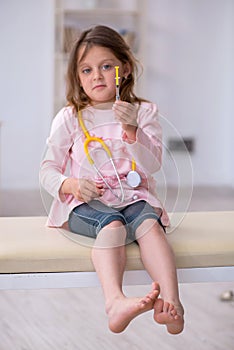 Small girl holding syringe waiting for doctor in the clinic