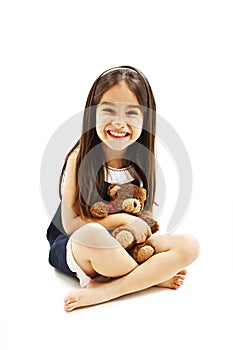 Little girl holding a teddy bear, sitting on floor