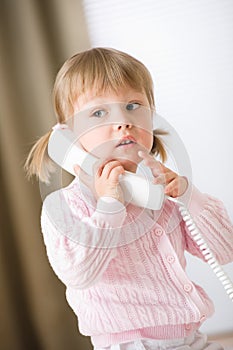 Little girl holding telephone receiver calling