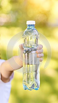 Little girl holding water bottle. Outdoor training. Thirsty