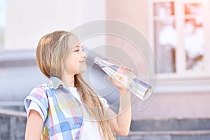 Little girl holding water bottle. Outdoor training. Thirsty. Glass drink