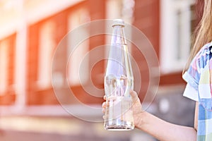 Little girl holding water bottle. Outdoor training. Thirsty. Glass drink