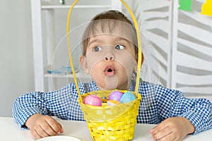 a little girl holds a basket of colored eggs