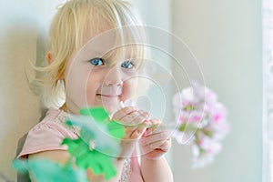 A little girl holds flowers in her hands and looks at the camera