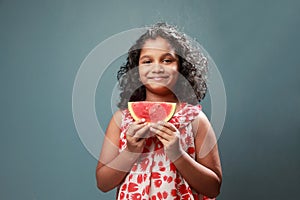 A little girl holds a slice of watermelon