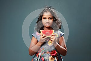 A little girl holds a slice of watermelon